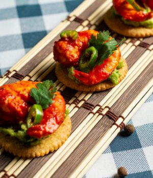 Tasty shrimp appetizers with guacamole and jalapeños served on crackers.